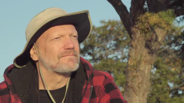 An older hiker looking through binoculars while on a scenic hike in the mountains alt