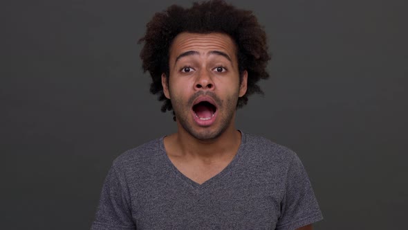 African American Young Male Yawning Isolated on Charcoal Background Smiling Afterwards alt