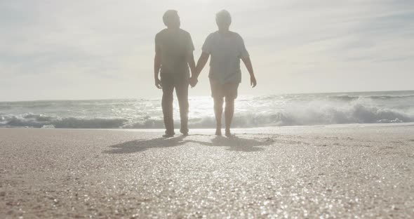 Latin hispanic couple holding hands, walking on beach at sunset alt