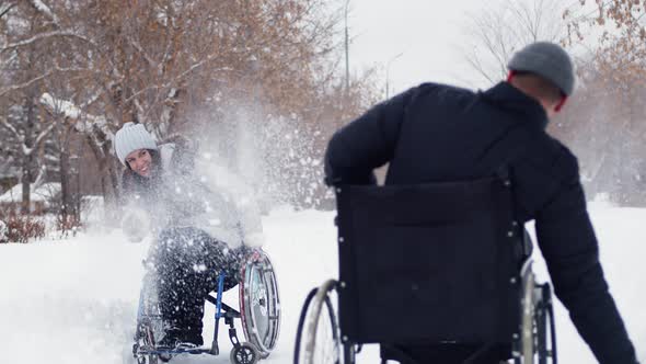 Disabled Man and Woman in Wheelchairs Play Snowballs in Winter at Park Having Fun alt