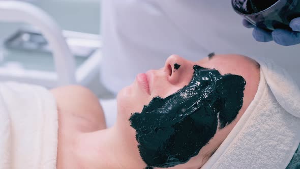 Cosmetologist Applies Alginate Mask with Spatula on Face of Woman