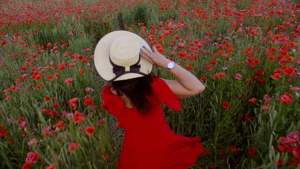 Young Girl in Red Runs Across a Poppy Field