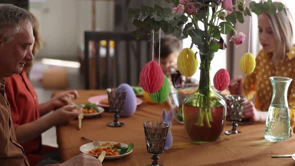Family is eating at Easter dinner sitting at the table at home alt