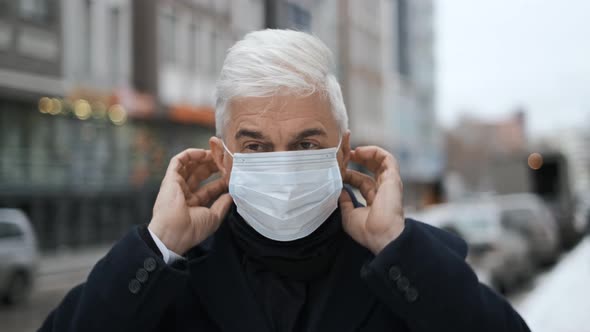Old Gray Haired Gentleman on Amsterdam Streets Puts on Coronavirus Face Mask