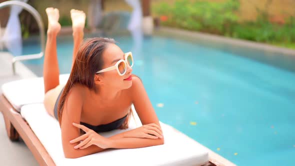 Young asian woman enjoy around outdoor swimming pool for leisure alt