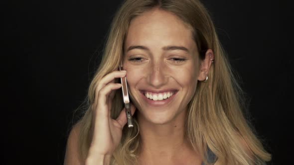 Young woman receiving good news and laughing while talking on cell phone alt