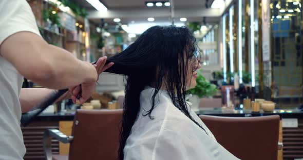 A Young Brunette Woman in a Beauty Salon Has a Haircut in a Barbershop in a Barbershop a Man Does a alt