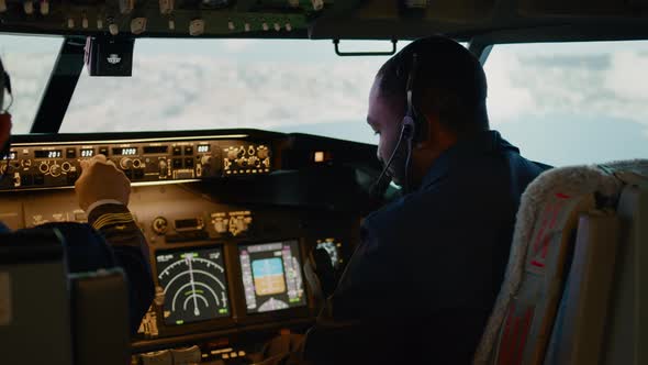 African American Copilot Flying Airplane with Captain in Cockpit alt
