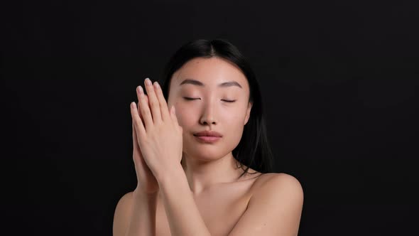 Young Beautiful Asian Lady with Bare Shoulders Applying Moisturizing Cream on Hands Smiling to alt