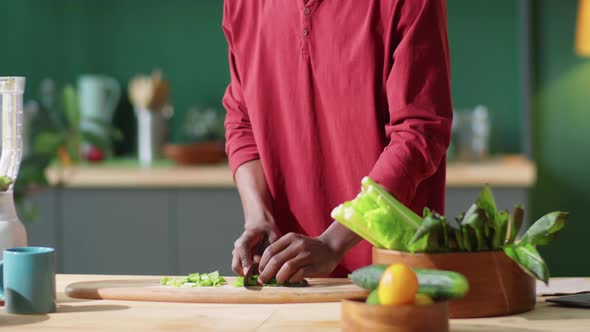 Afro-American Man Cutting Green Salad Leaves at Home alt
