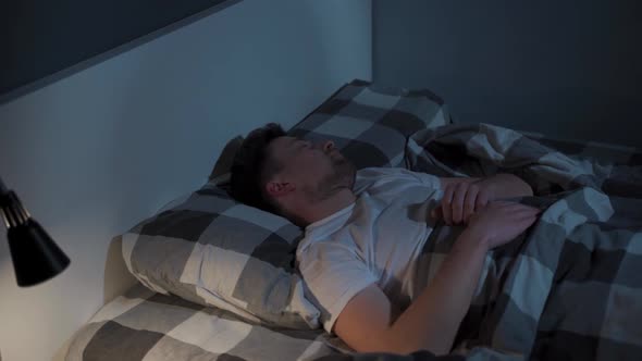 A Worried Man Cannot Sleep and Twists and Turns in Bed Covered with a Blanket at Night with the alt