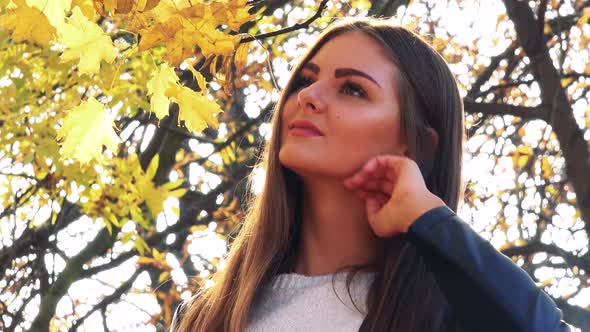 Young Beautiful Woman Smiles To Camera in the Park in Autumn Day - Closeup alt