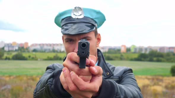 A Young Police Officer Aims a Gun at the Camera  alt