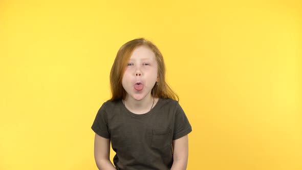 Funny Red-haired Girl Smiles Into the Camera and Shows Tongue alt