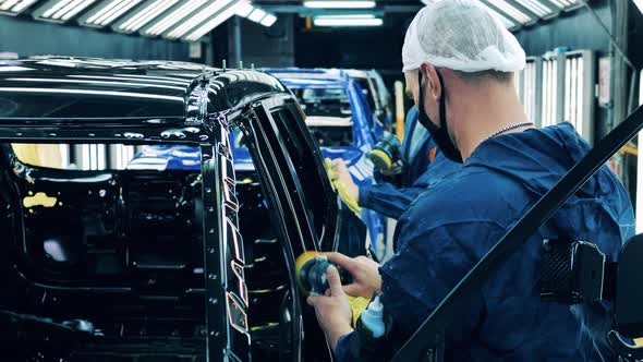Factory Workers Are Polishing Unfinished Car Body. Automotive Industry Concept alt
