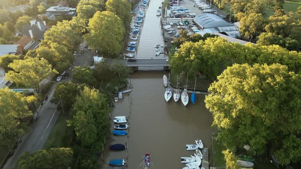 Aerial flying over port with boats and yachts docked in San Isidro city at golden hour alt