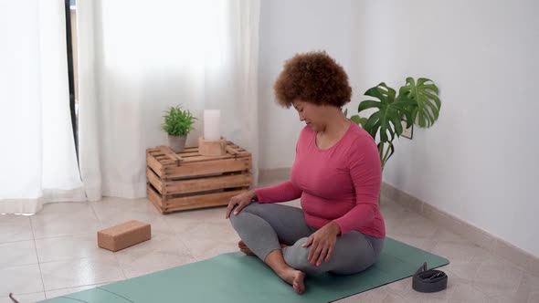 Senior african woman doing yoga meditation at home