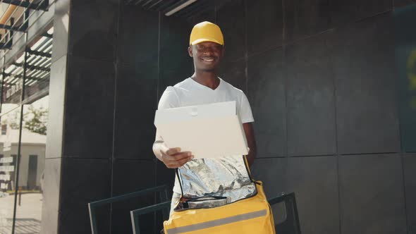 A Handsome AfricanAmerican Courier Charmingly Smiling at the Camera Pulls a alt