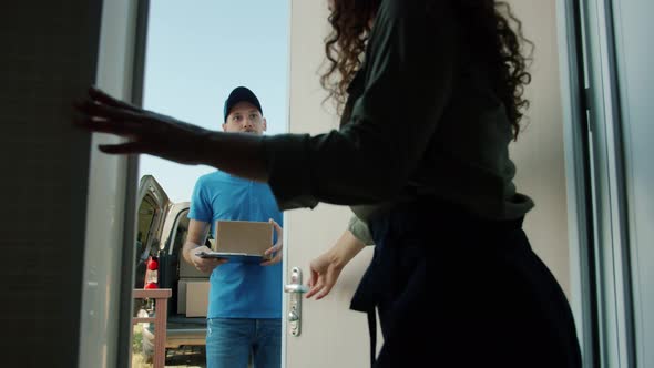 Slow Motion of Woman Opening Front Door Taking Parcel From Delivery Man Signing Paper alt