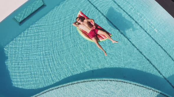 Drone Over Man Floating On Inflatable In Pool alt