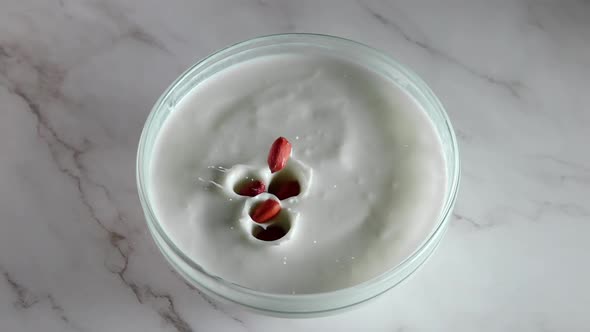 Peanuts Fall Into Thick White Yogurt