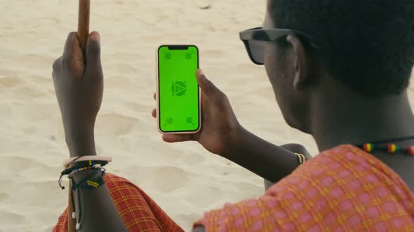 African Maasai Male Hand Holding a Smartphone with Green Screen and Swiping in the Front of Desert