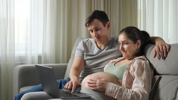 Husband and Wife Do Online Shopping for Future Baby Hugging alt