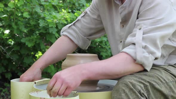 Male Potter of Caucasian Ethnicity Aligns a Clay Pot with a Wooden Tool Closeup alt