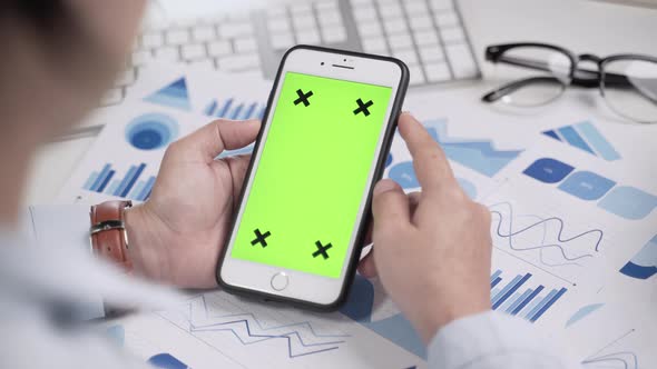 Businesswoman working and looking at green screen on smartphone