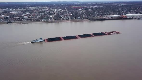 Aerial view of a tug boat pushing a barge filled with coal cruising on Louisville Kentucky Ohio rive alt