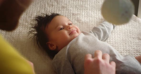 Happy Young Father Playing with a Newborn Baby Lying in a Child Crib alt