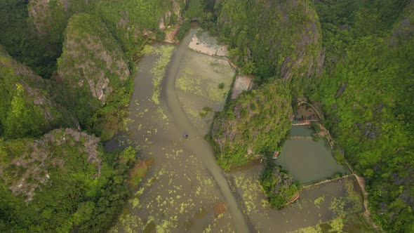 Aerial Shot of Beautiful Limestone Mountains with Passes Carved By a River in Ninh Binh Region a alt