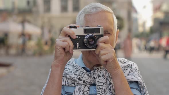 Senior Male Tourist Exploring Town and Makes a Photo with Retro Photo Camera alt