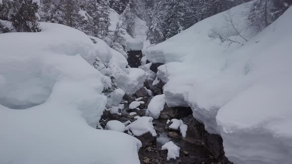 winter wonderland in the alps. A small valley with a snowy creek, Kleinwalsertal, Austria. Drone fly alt