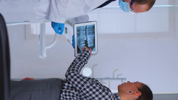 Dentist in Waiting Room Talking with Woman Patient About Xray alt