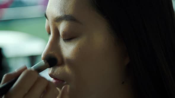 Makeup artist applying foundation on womens face