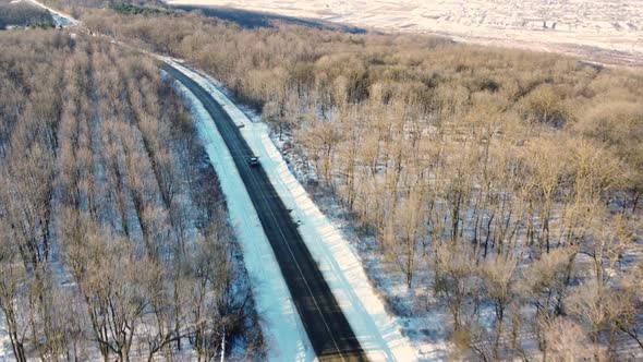 Aerial Of Car Driving Through A Forest Covered In Snow