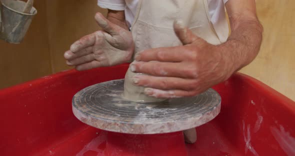 Senior caucasian man wearing apron and forming pottery in his workshop alt