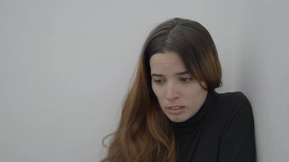 Young Scared Woman Sits in Corner of Room and Looks Down Close Slomo alt