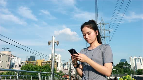 Asian woman athletes using smartphones typing sending messages on social media after running.