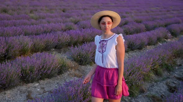 Woman in a Short Purple Dress and a Hat Stands on a Lavender Field alt