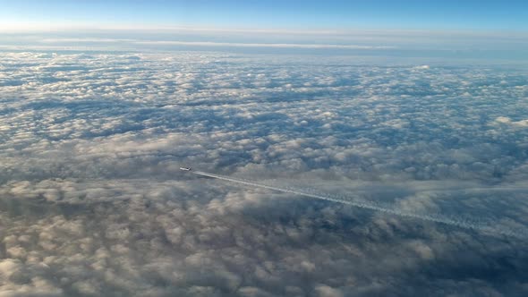 Incredible view from the cockpit of an airplane flying high above the clouds leaving a long white co alt