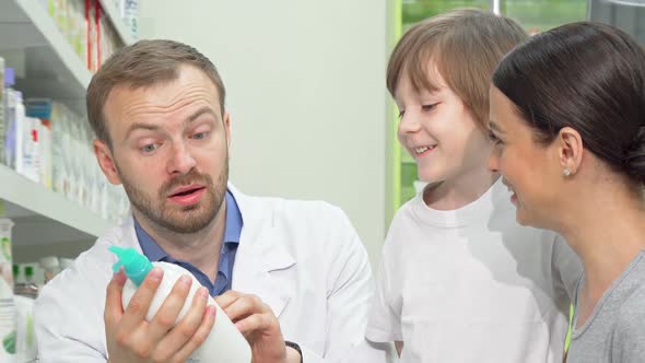 Cheerful Male Pharmacist Helping Young Woman with Little Son