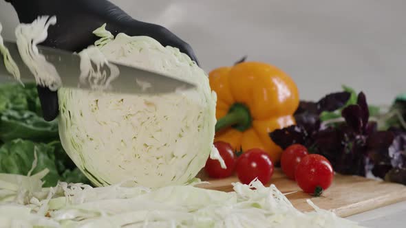 Chef Cuts the Cabbage with a Knife in Slow Motion Making a Salad Fresh Vegetables on a Cutting Board alt