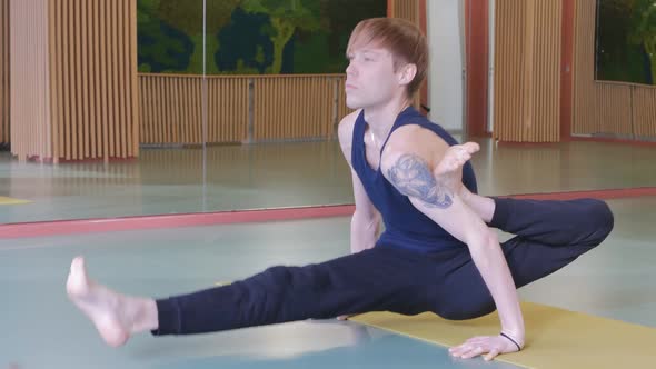 a Young Handsome Man Is Doing Yoga in an Empty Hall on a Yellow Carpet