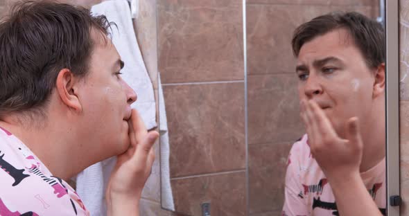 Man Puts Lotion on Skin After Shaving Looking in Mirror