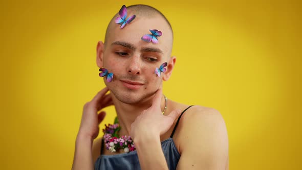 Portrait of Cheerful Male Caucasian Queer with Butterflies on Face in Dress and Floral Necklace alt