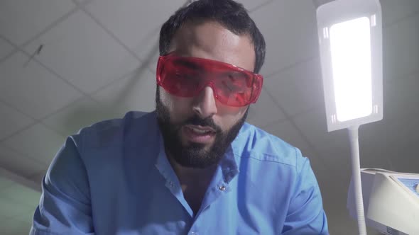 Professional Middle Eastern Dentist Using Instruments on Camera. Portrait of Man in Protective alt