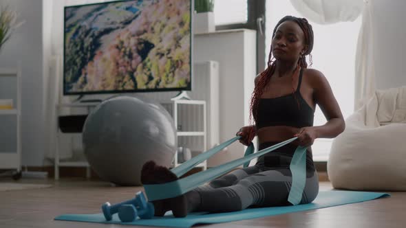 Athlete with Black Skin in Sportswear Exercising Body Muscle Using Fitness Elastic alt