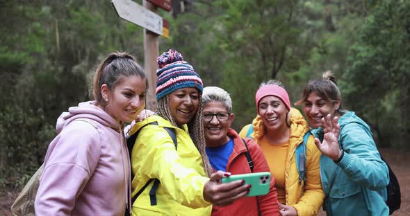 Multi generational women having fun during trekking day taking using mobile phone for video call alt